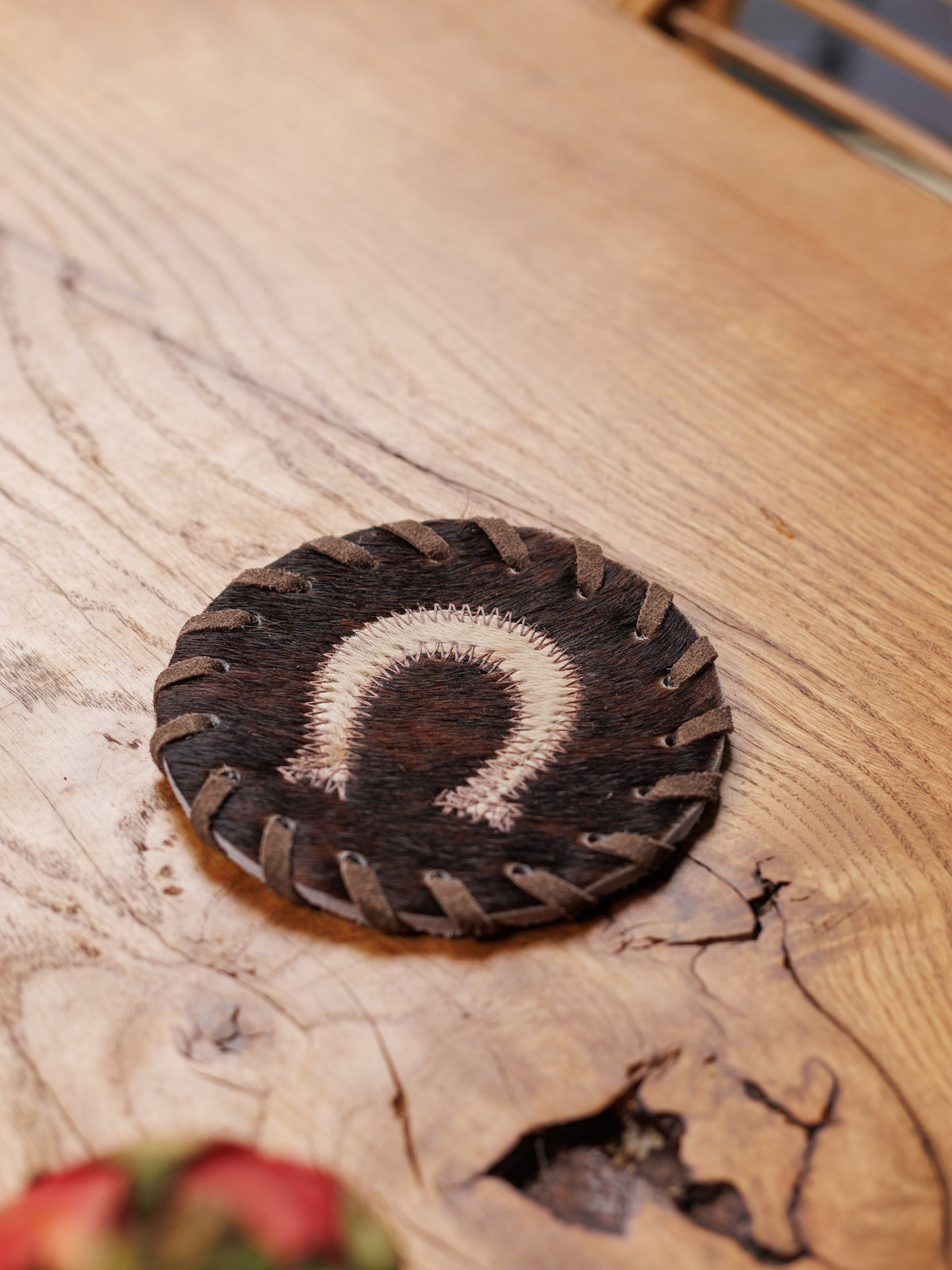 A cowhide coaster with a horseshoe on a wooden table, close up