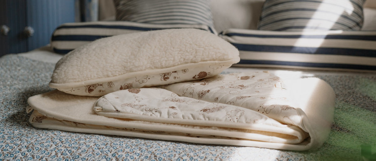 Folded wool underblanket and pillow on a bed