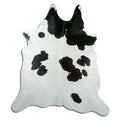 Black and white cowhide rug of about 230 × 210 cm, seen from above: the exact hide you receive