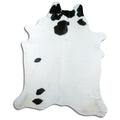 Black and white cowhide rug of about 230 × 190 cm, seen from above: the exact hide you receive