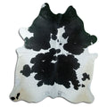 Black and white cowhide rug of about 230 × 190 cm, seen from above: the exact hide you receive
