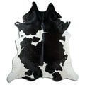 Black and white cowhide rug of about 250 × 220 cm, seen from above: the exact hide you receive