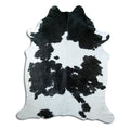 Black and white cowhide rug of about 220 × 190 cm, seen from above: the exact hide you receive