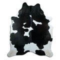 Black and white cowhide rug of about 220 × 190 cm, seen from above: the exact hide you receive