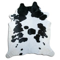 Black and white cowhide rug of about 240 × 210 cm, seen from above: the exact hide you receive