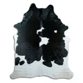 Black and white cowhide rug of about 230 × 190 cm, seen from above: the exact hide you receive