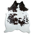 Black and white cowhide rug of about 240 × 200 cm, seen from above: the exact hide you receive