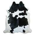 Black and white cowhide rug of about 220 × 190 cm, seen from above: the exact hide you receive