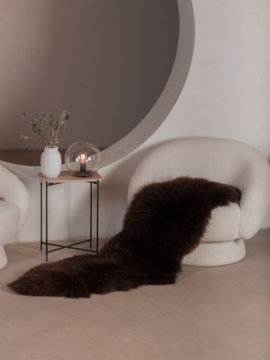Brown sheepskin runner on the floor beside a white armchair