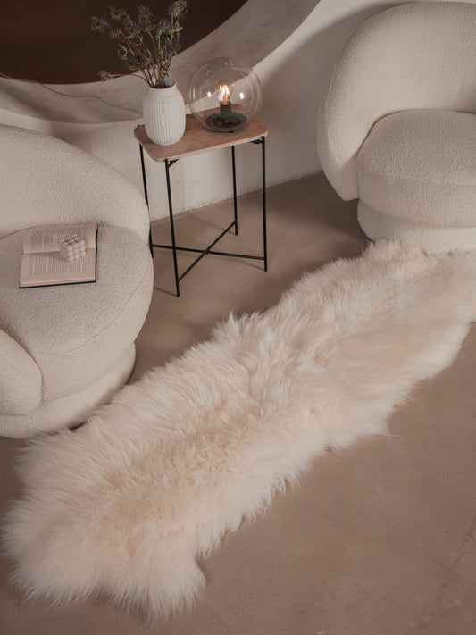 White sheepskin runner of about 180 × 60 cm on the floor between two armchairs