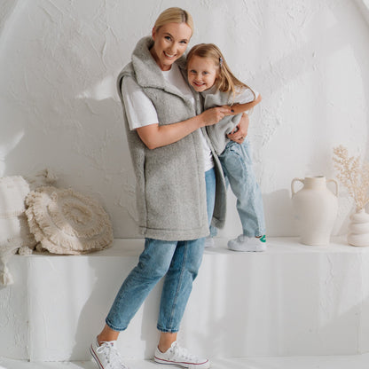 A woman in the grey Wave merino vest with a child