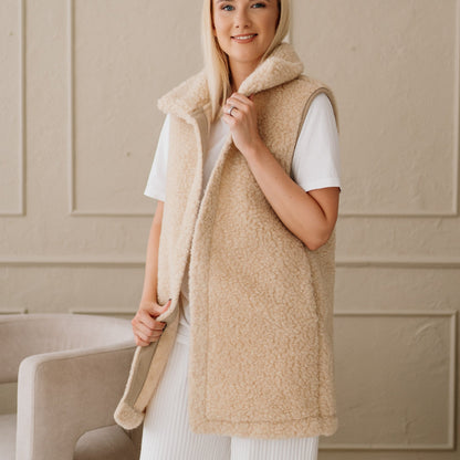 The beige Wave merino vest with its hood down, front