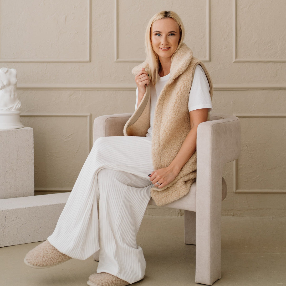 The beige Wave merino vest worn seated