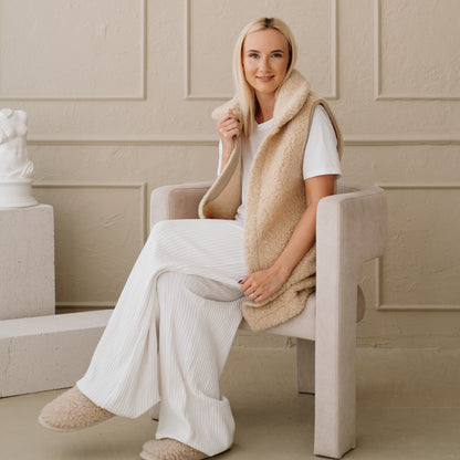 The beige Wave merino vest worn seated