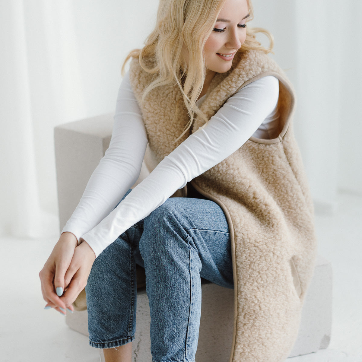 The beige Pearl merino vest worn with a white top and jeans