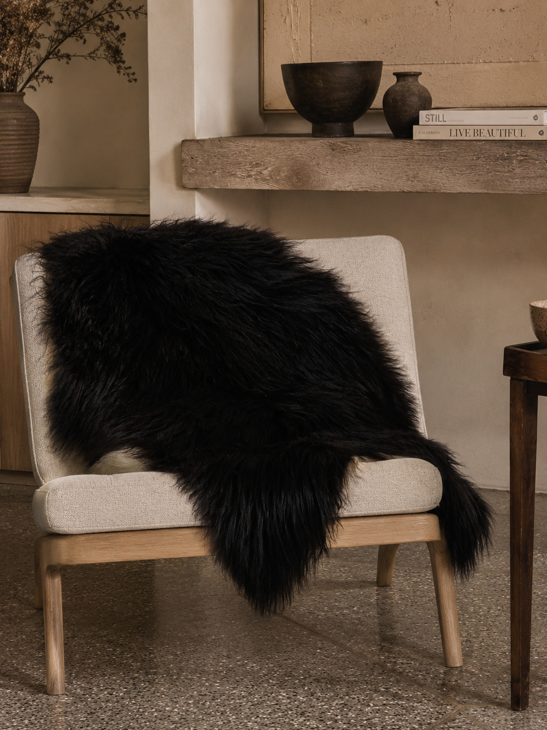 Black Icelandic sheepskin draped over a wooden lounge chair