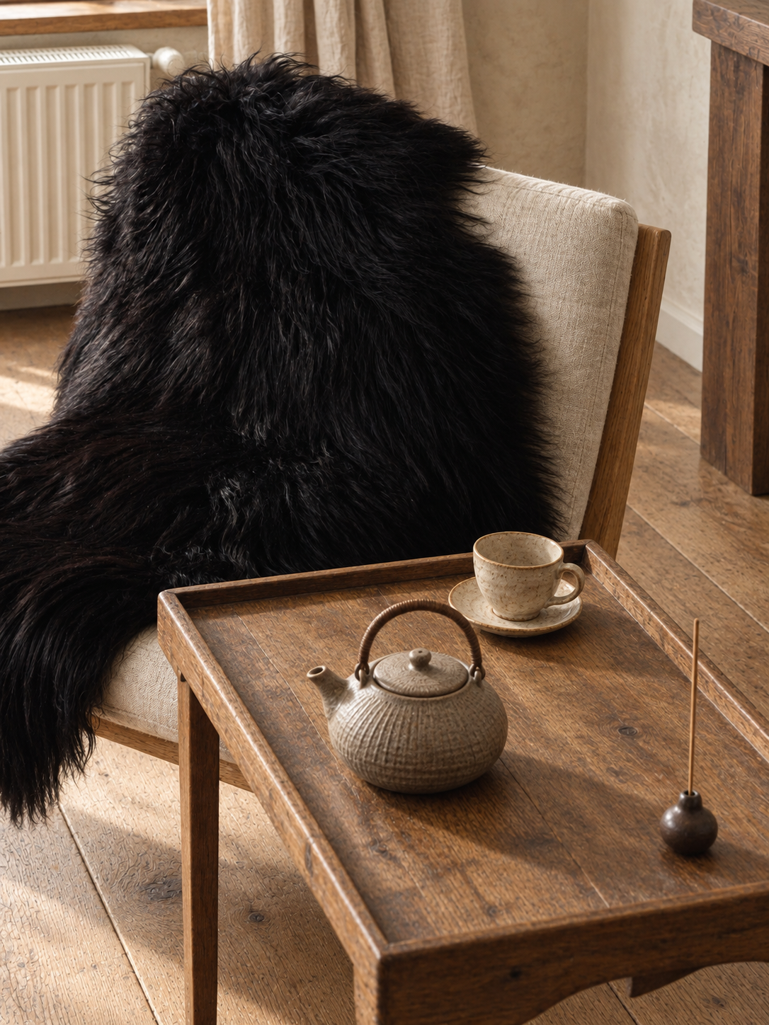Black Icelandic sheepskin over a wooden armchair beside a coffee table