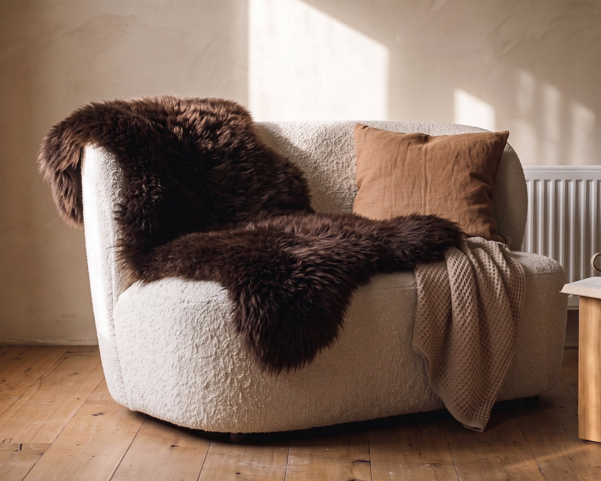 Brown sheepskin rug and a cushion on a bouclé armchair