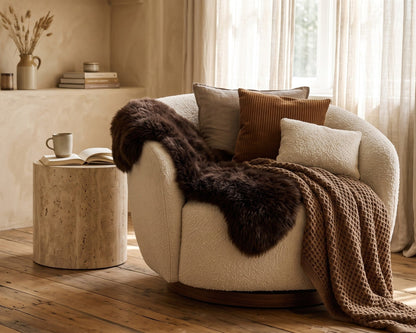 Brown sheepskin rug over a round bouclé armchair in a sunny living room
