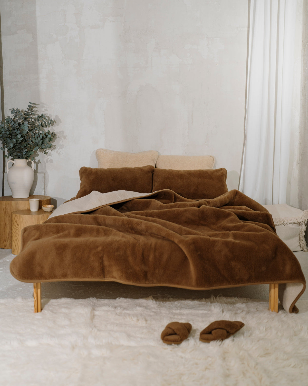 Camel wool blanket on a bed in a light bedroom