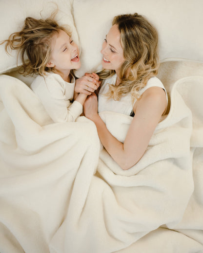 An adult and a child cuddled up under the Cashmere wool blanket