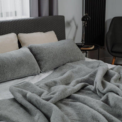 Meringue 2-ply merino blanket on a bed with wool pillows