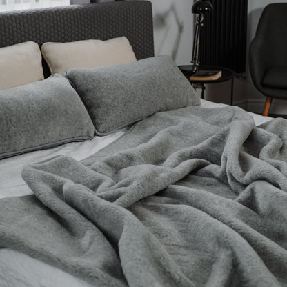 Meringue merino blanket on a bed with wool pillows