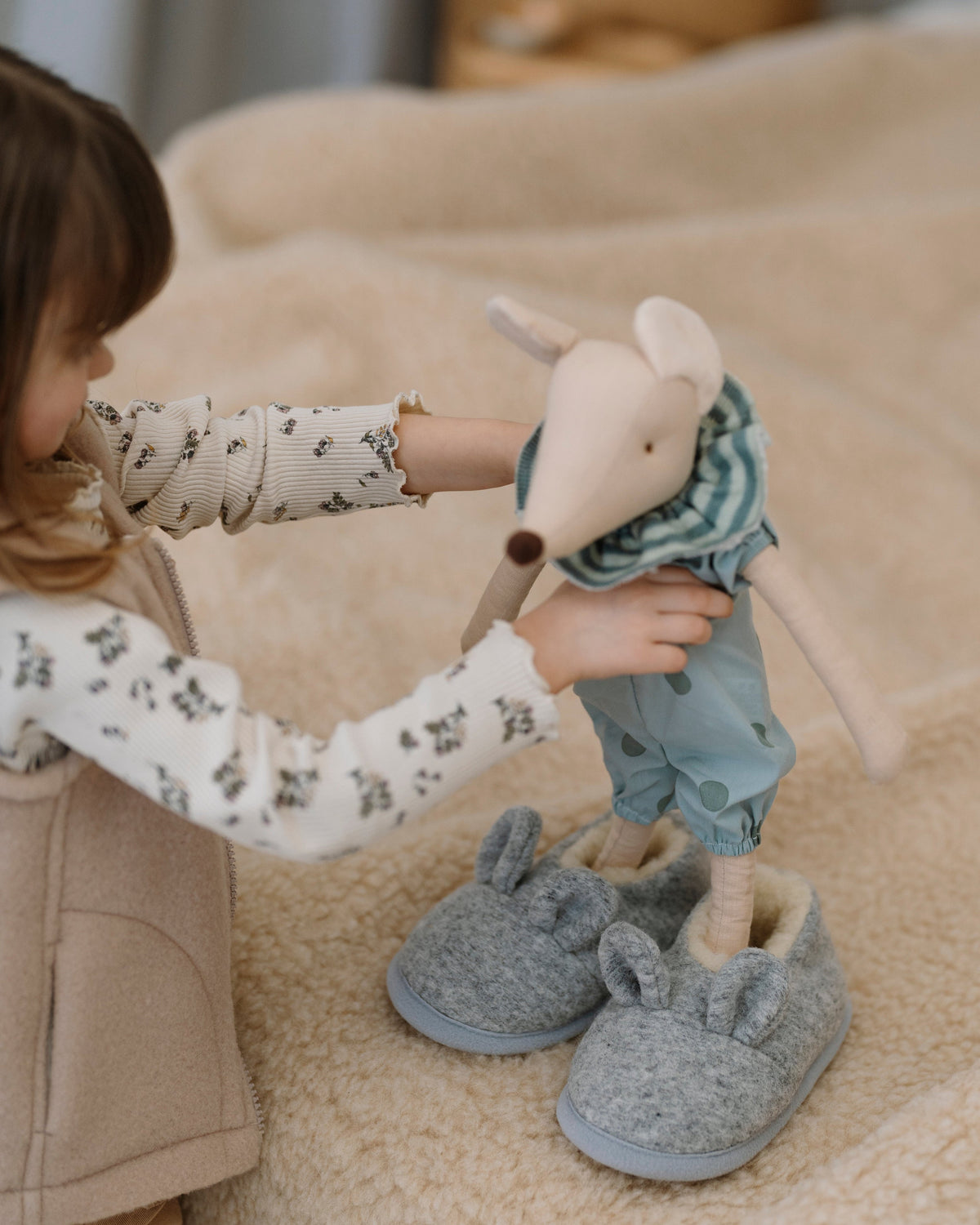 A child holding a toy, wearing Mouse merino slippers