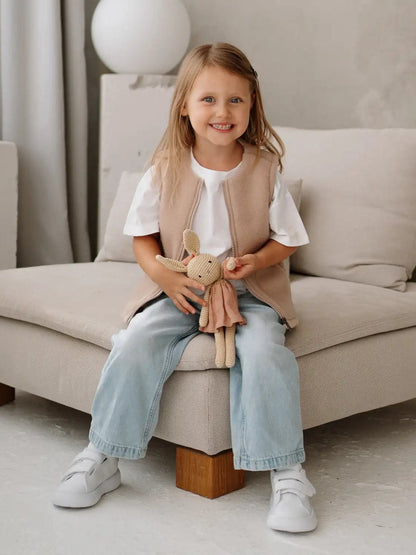 A girl on a sofa wearing the Lama merino vest