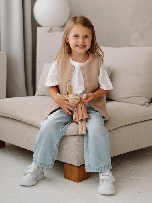 A girl on a sofa wearing the Lama merino vest