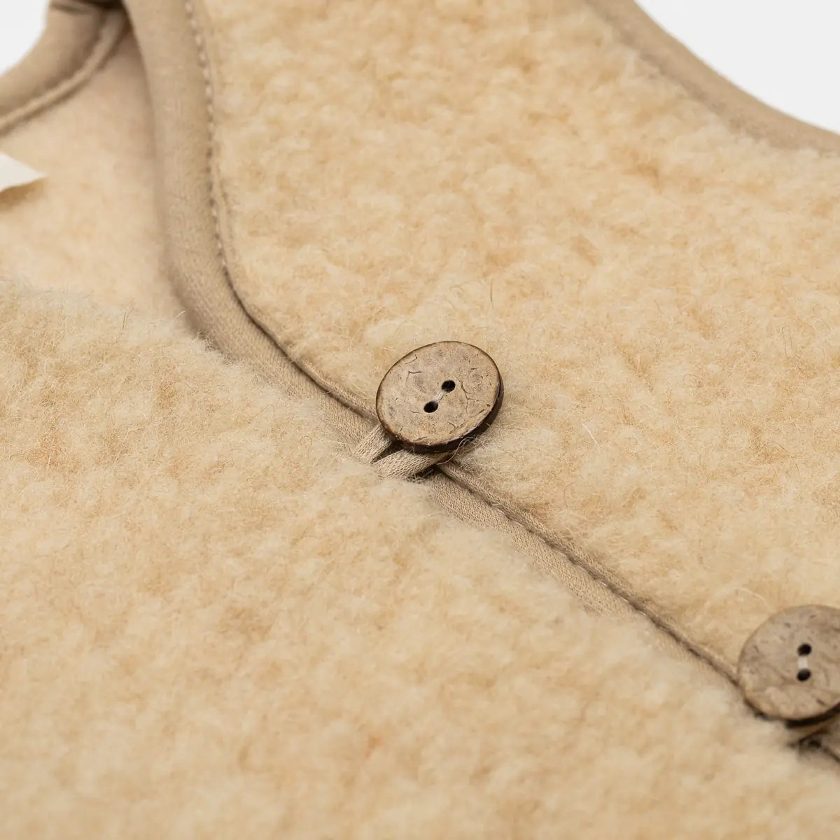 Close-up of a button on the Panda merino vest