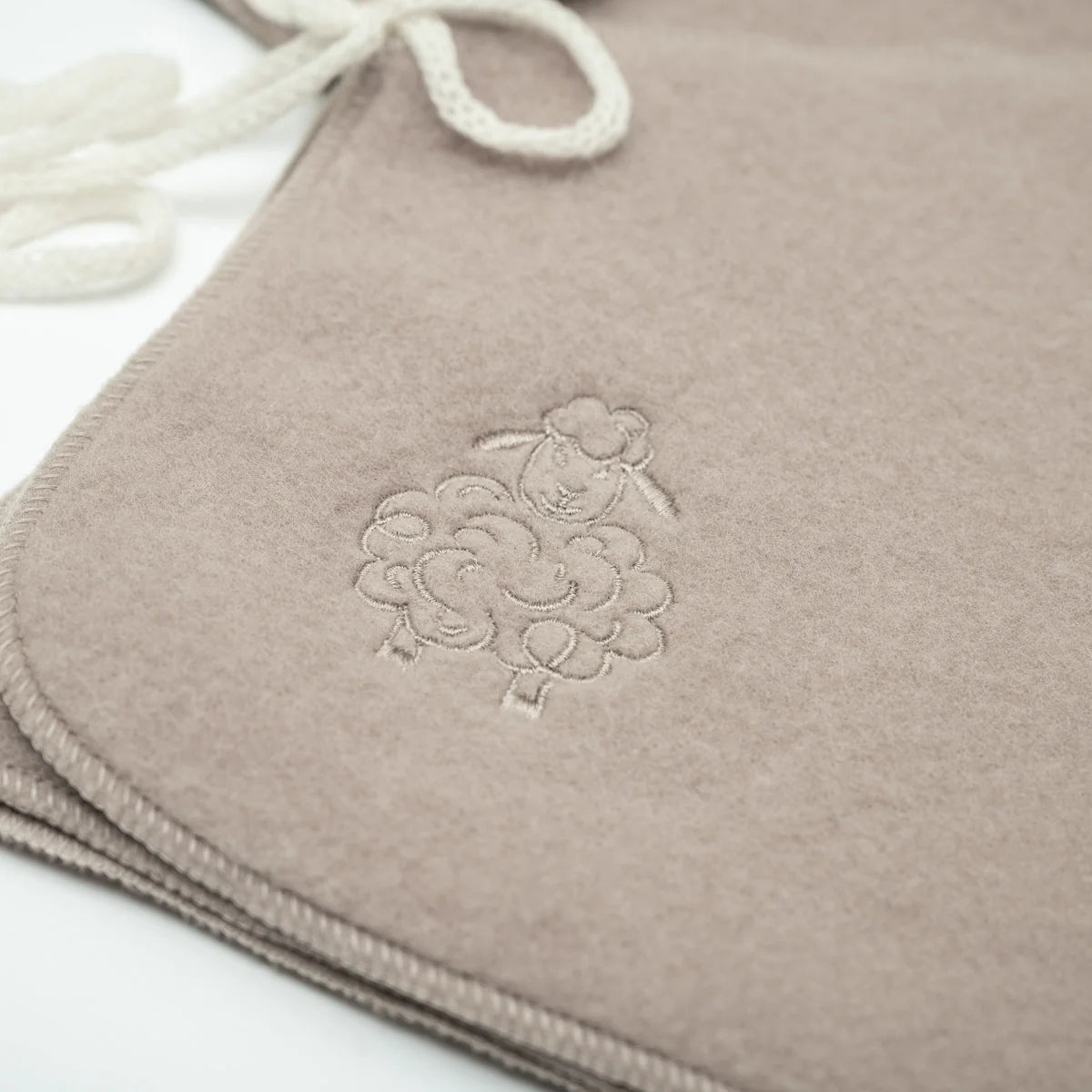 Close-up of the embroidered sheep on the beige baby jacket