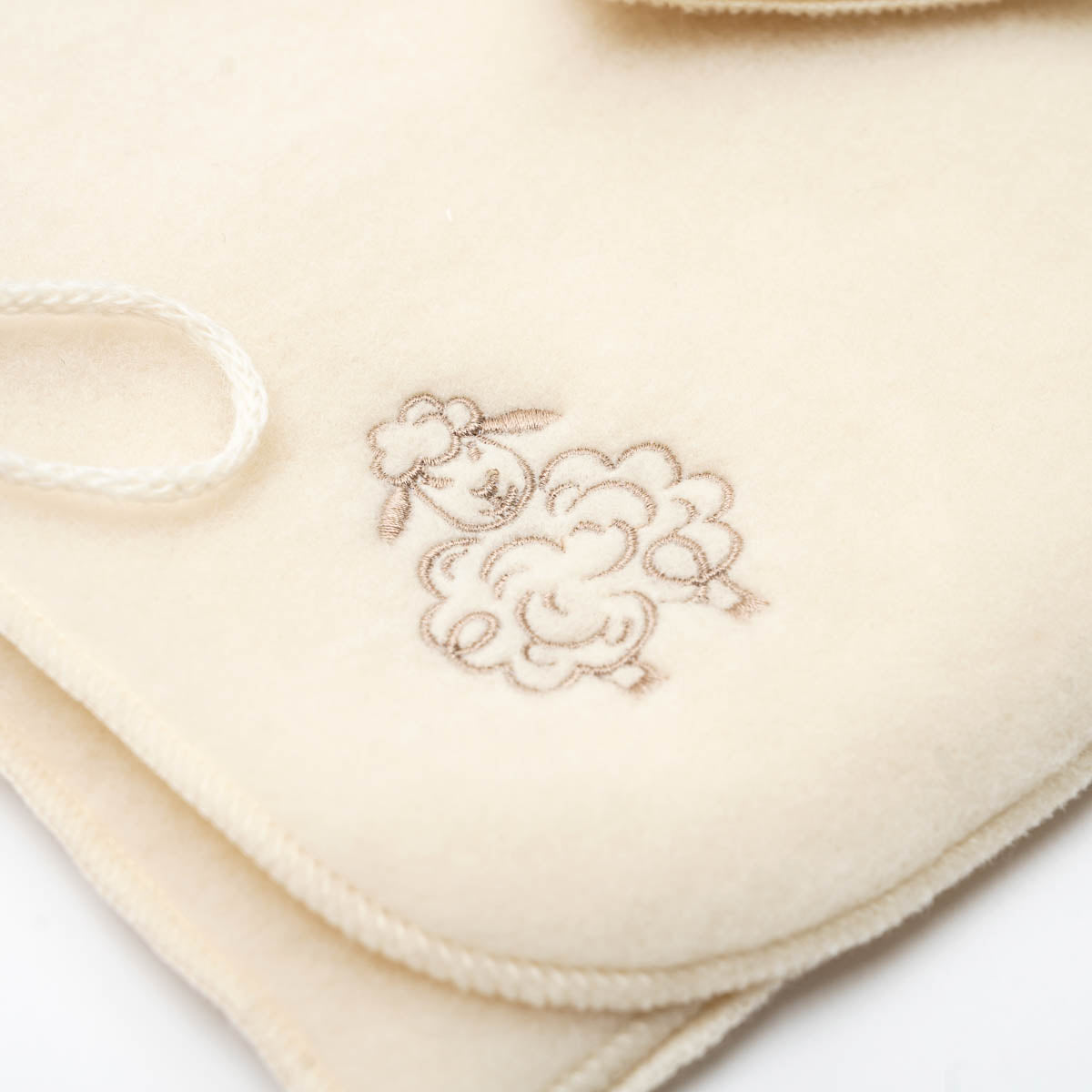 Close-up of the embroidered sheep on the ecru baby jacket