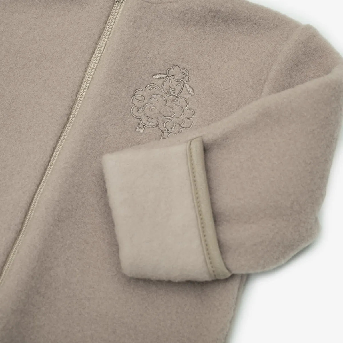 Close-up of the embroidered sheep and the fold-over cuff on the beige romper