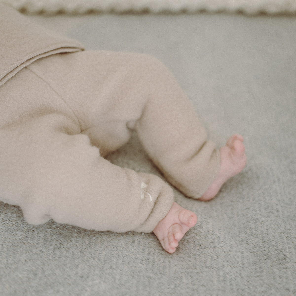 A baby's legs in the beige merino trousers