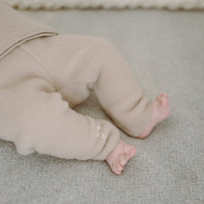 A baby's legs in the beige merino trousers