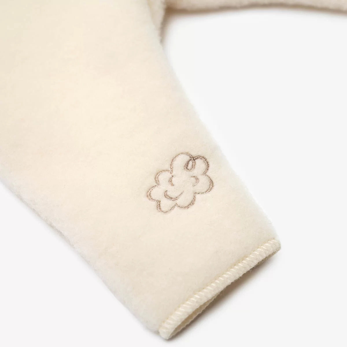 Close-up of the embroidered sheep on the ecru baby trousers