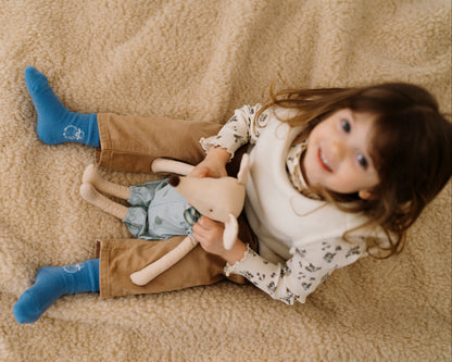 A child with a toy sitting on the Almond merino blanket