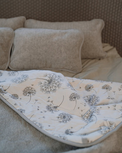 Dandelion blanket on a bed with the printed side turned back