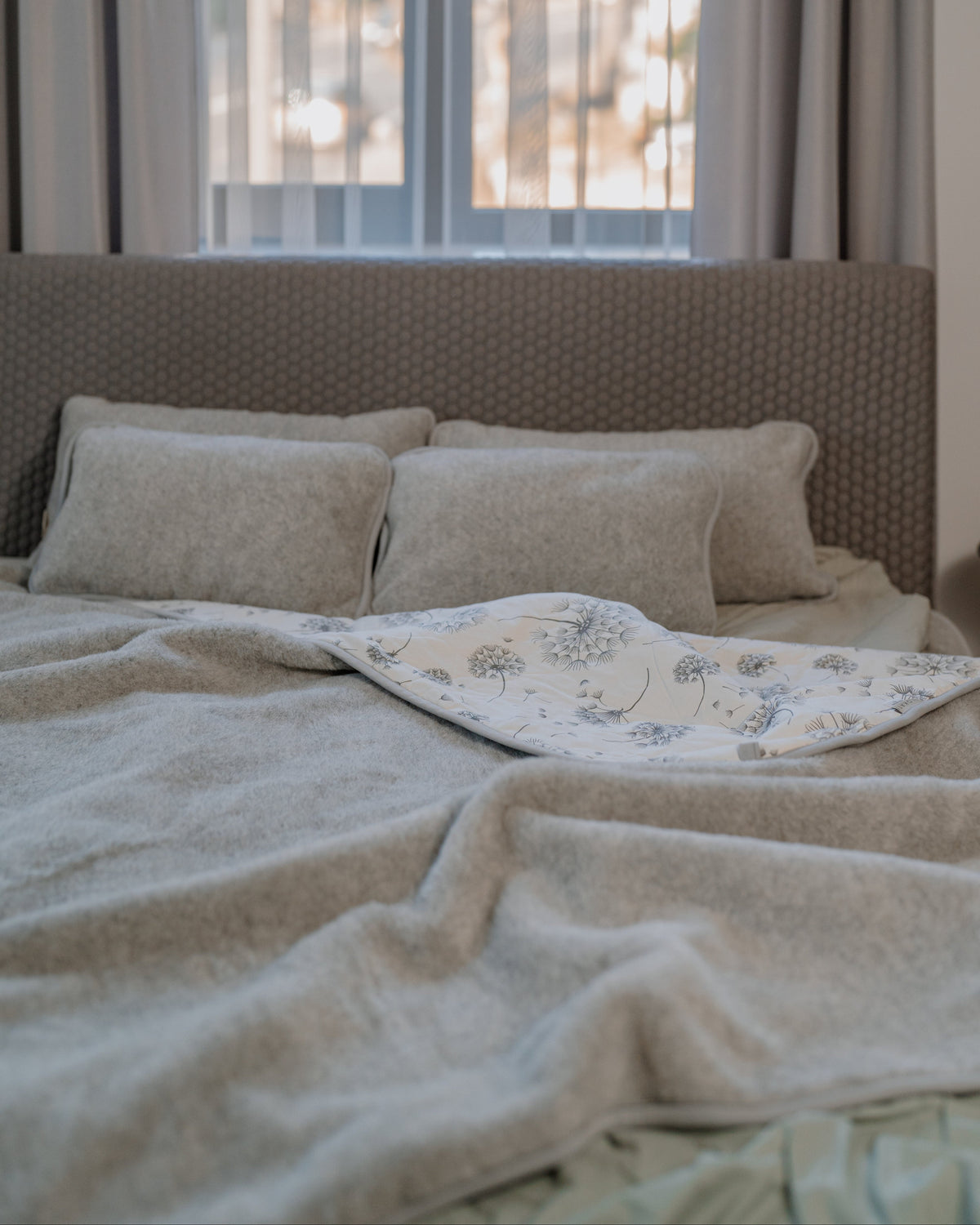 Dandelion merino blanket on a bed with wool pillows