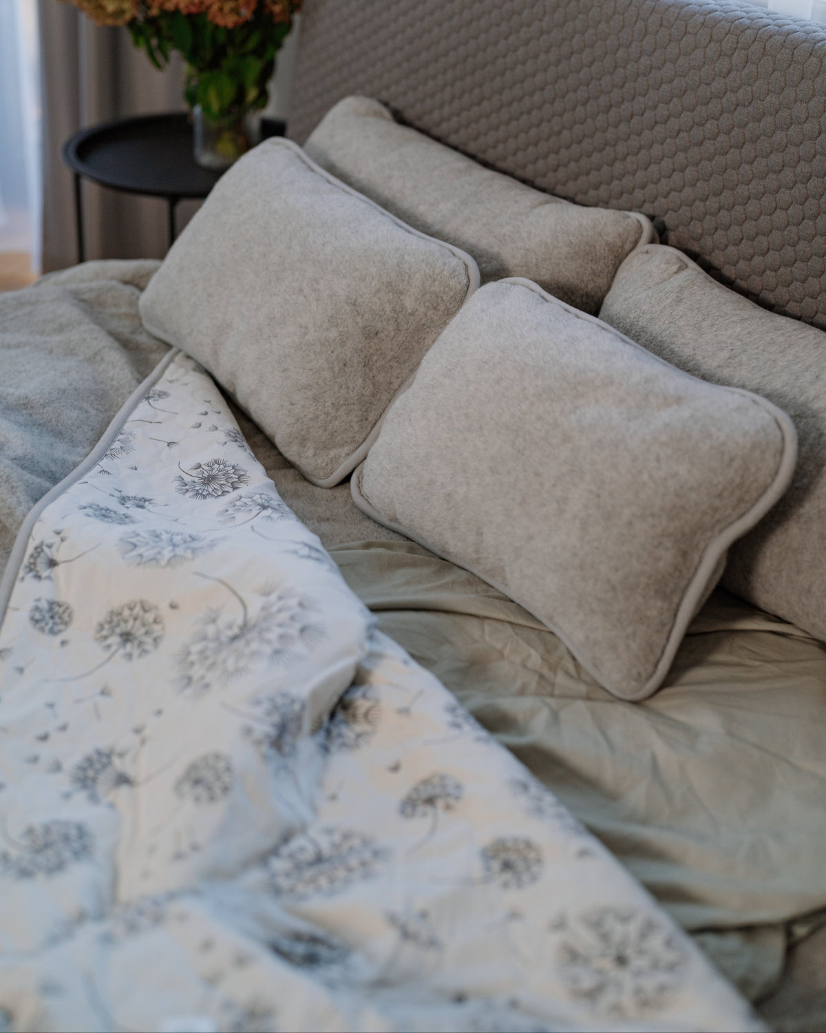 Dandelion blanket on a bed, merino side and printed side