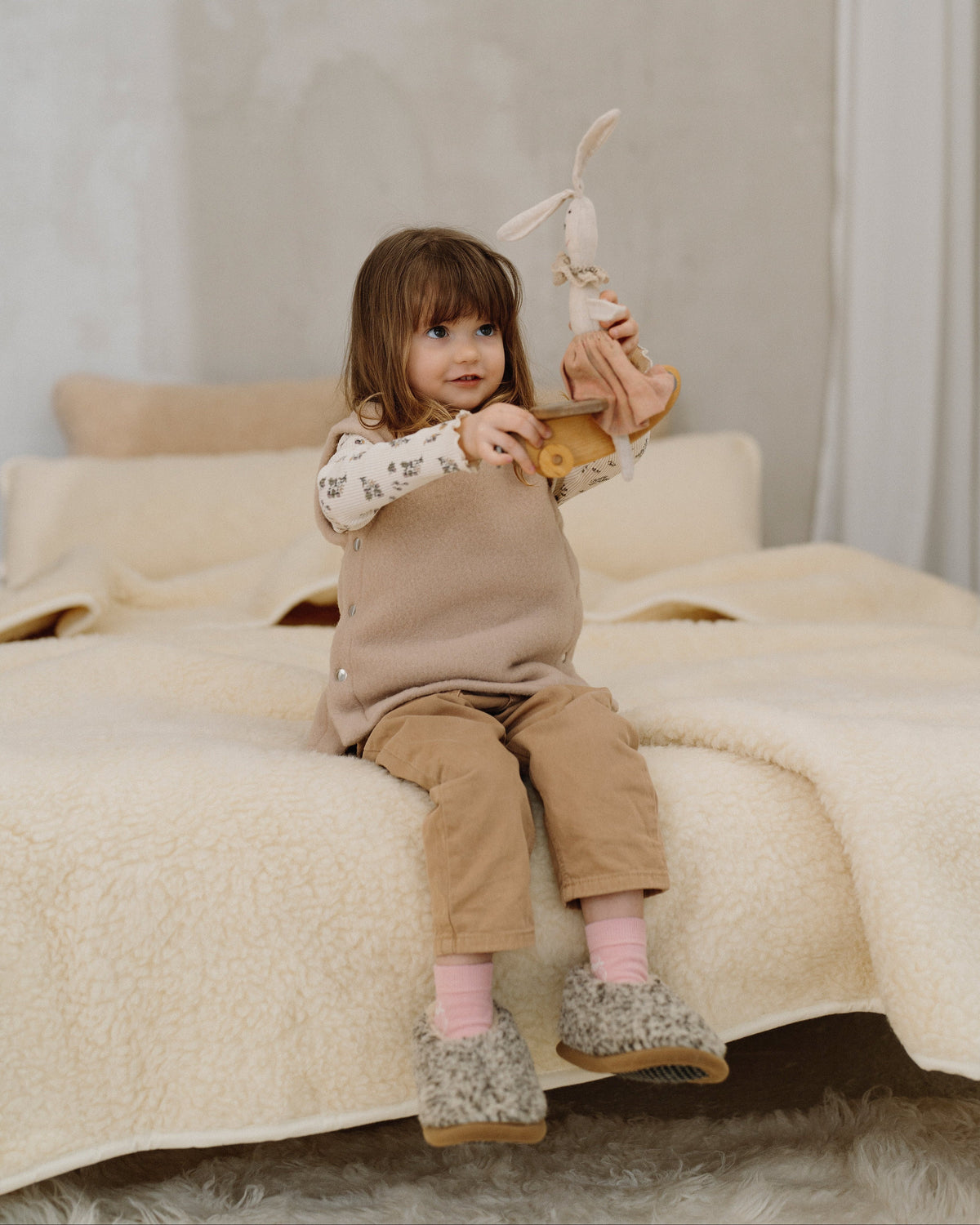 A child sitting on a bed with the Luka merino blanket