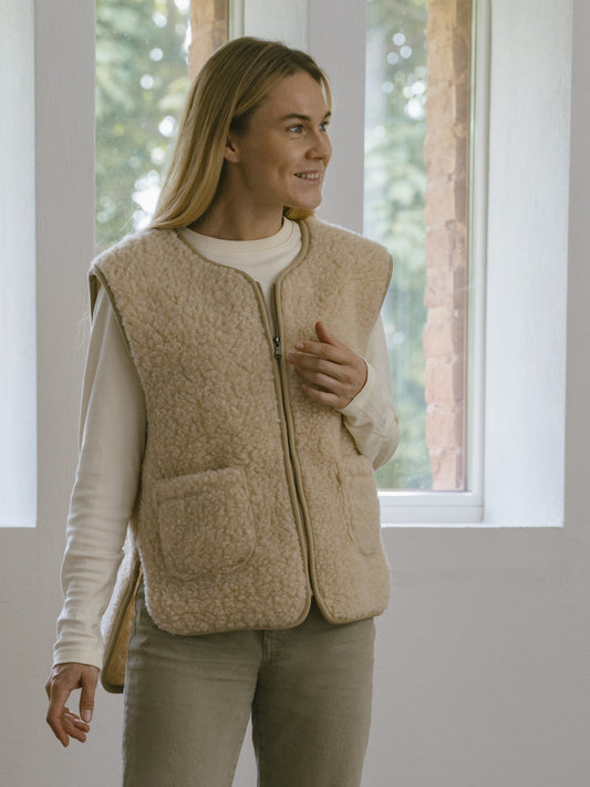 A woman wearing the Island merino vest in beige