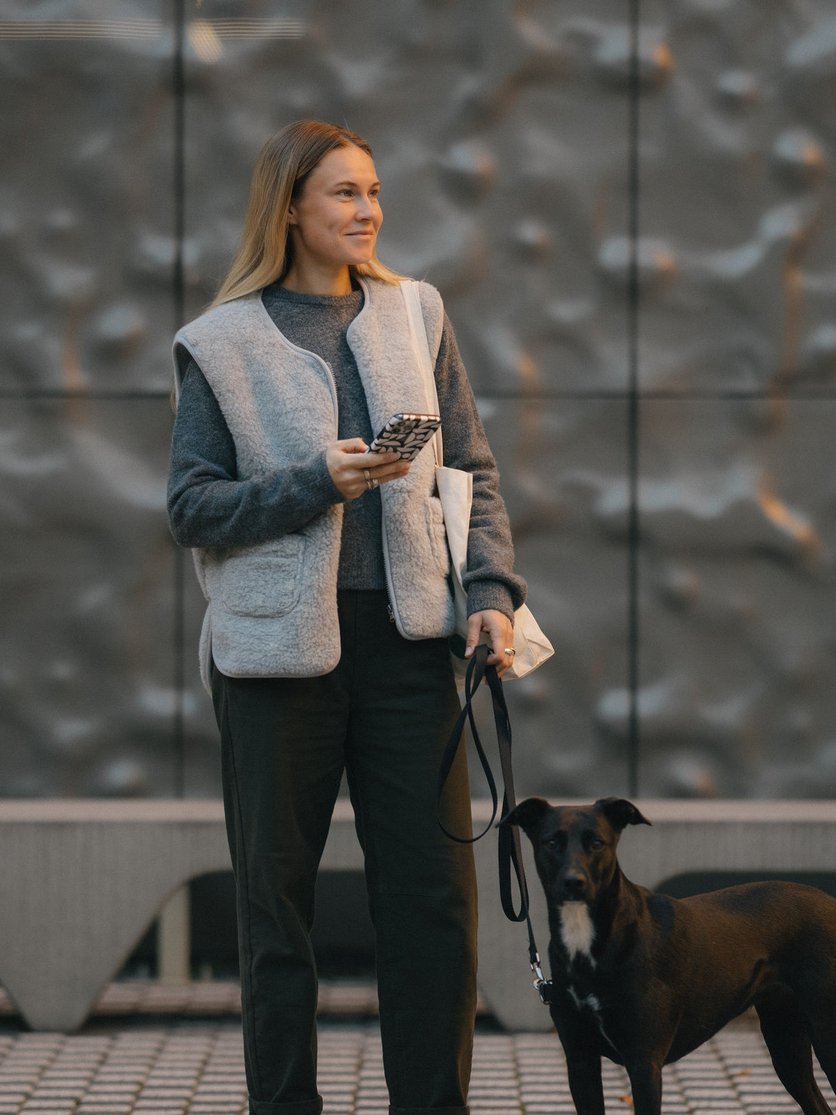 A woman with a dog, wearing the Island merino vest in grey