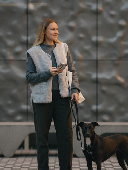 A woman with a dog, wearing the Island merino vest in grey