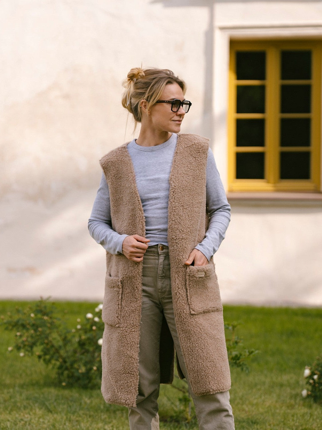 A woman wearing the long Sea merino vest in beige