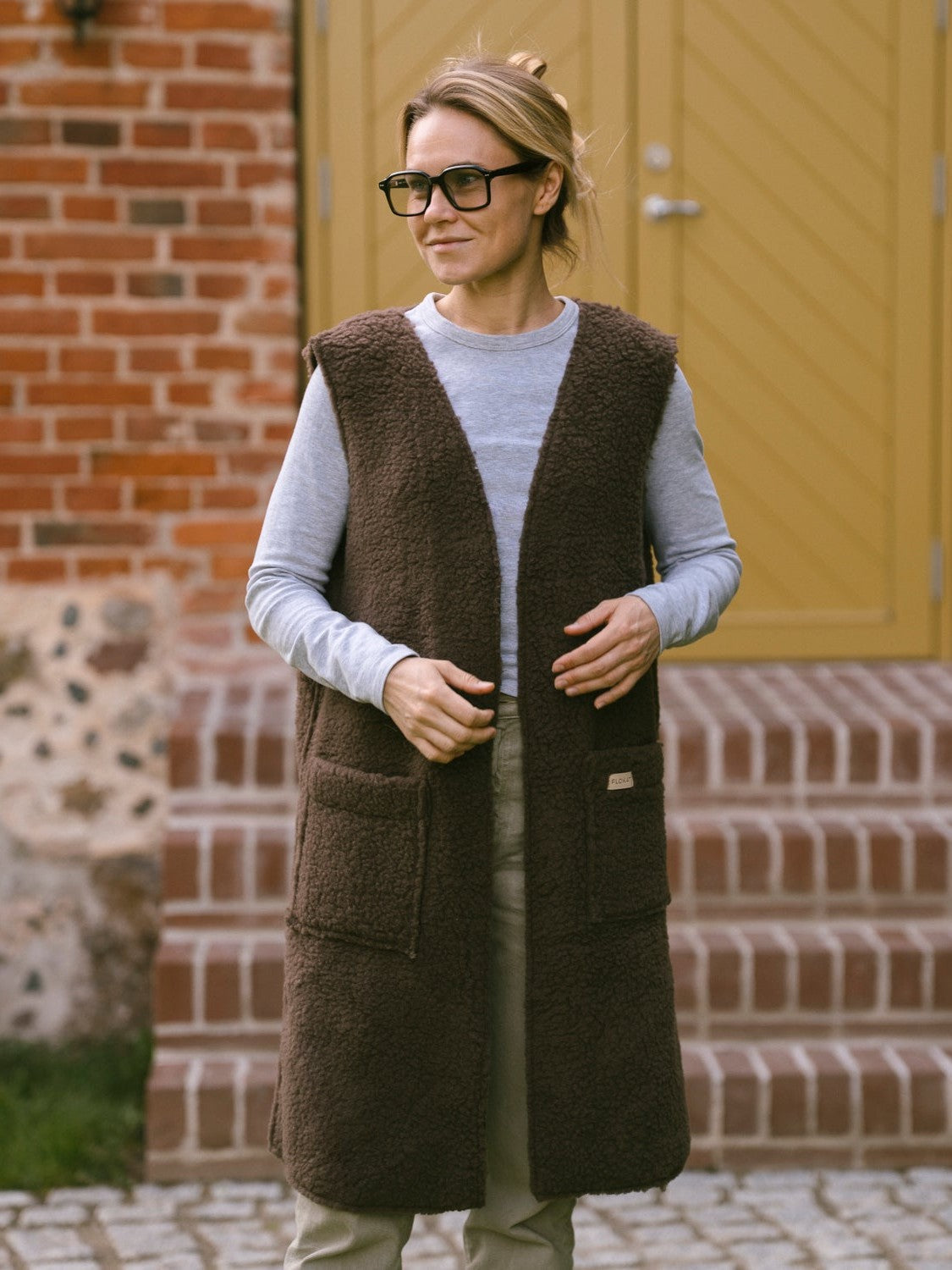 A woman wearing the long Sea merino vest in brown