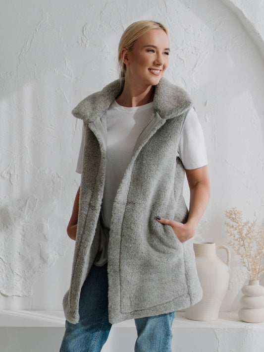 A woman wearing the Wave merino vest in grey